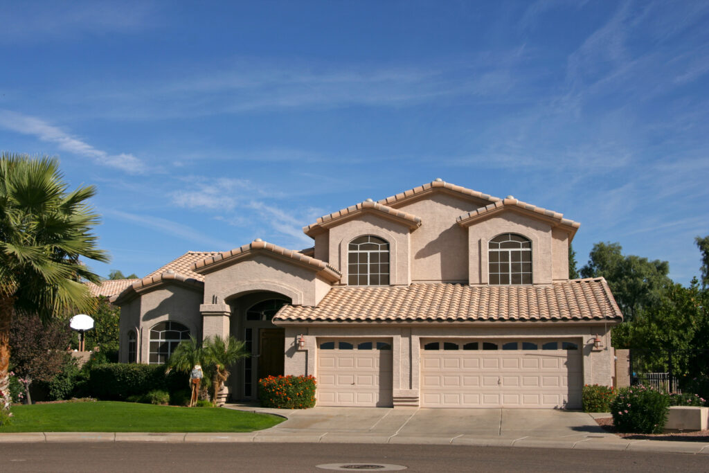 Large, modern stucco home in Glendale, Arizona, with a tile roof, two arched windows, and a manicured lawn, ideal for home services.